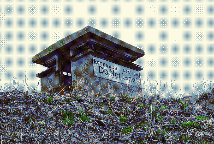 A picture of an abandoned cement building with ''RESEARCH STATION: DO NOT LAND'' painted on the side.