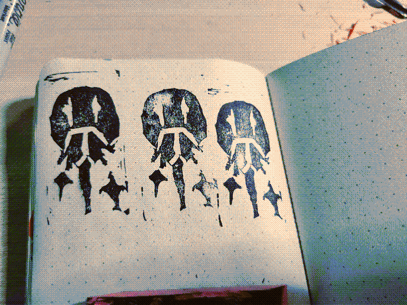 A picture of inky horseshoe crab stamps in a sketchbook, they are quite rough around the edges because it was the artist's first time making an eraser stamp.